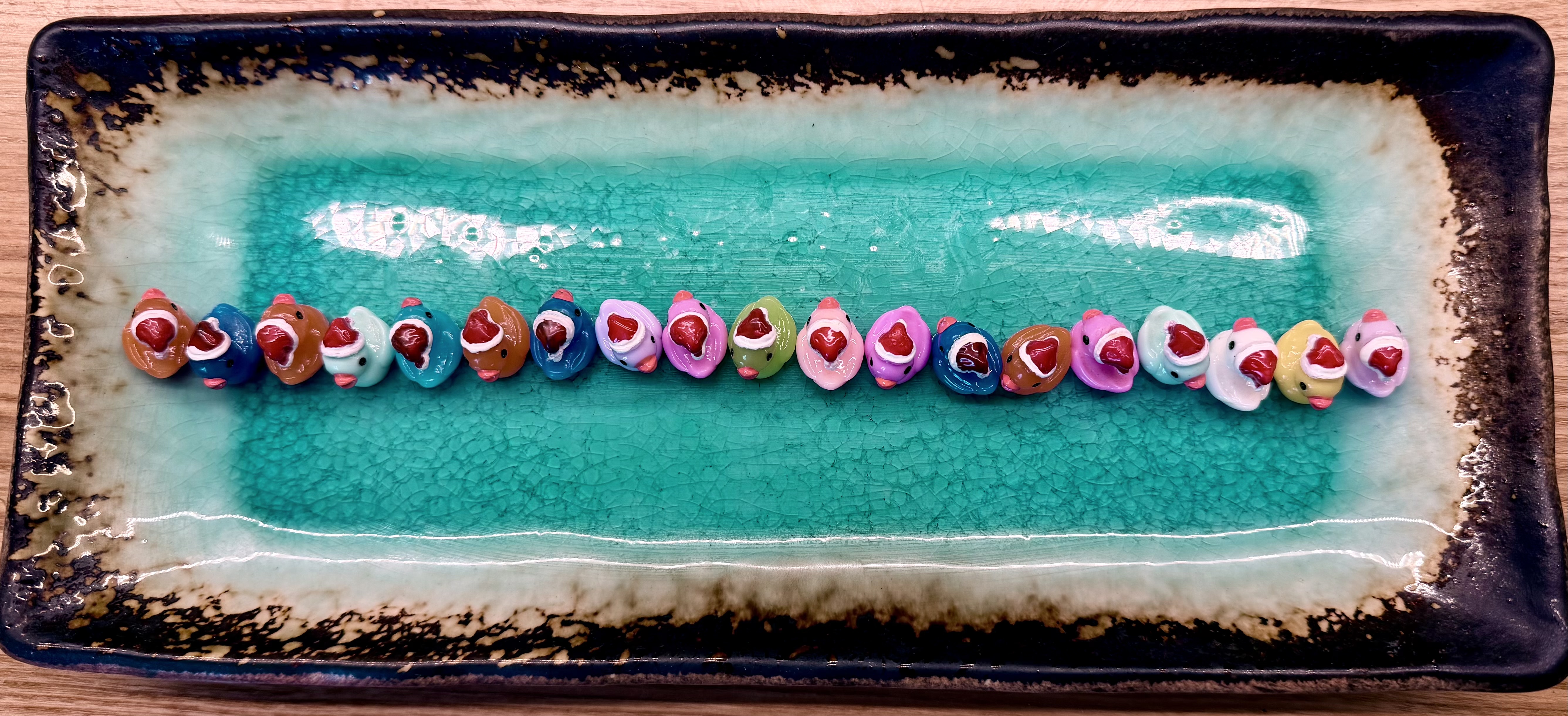 Small plastic ducks in santa hats, neatly lined up